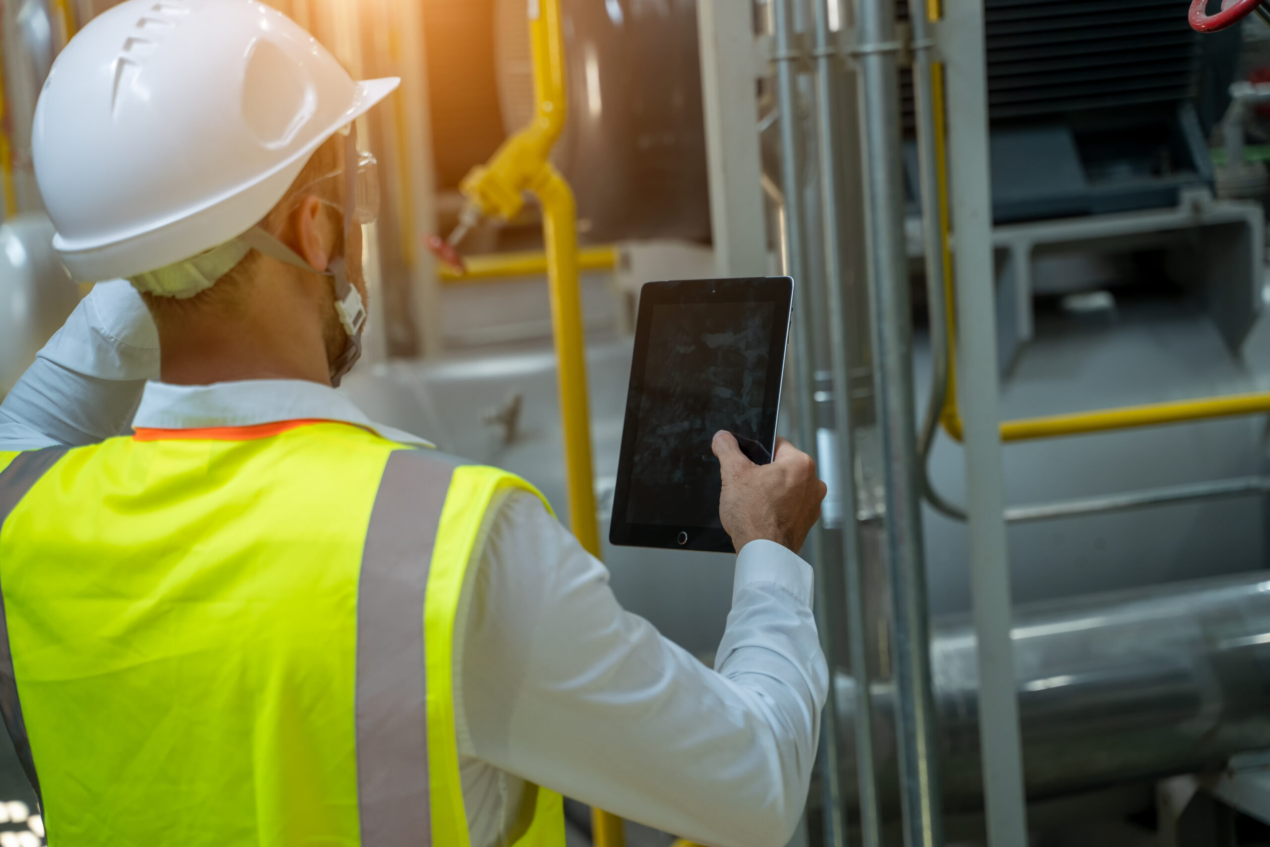 portrait of electrician engineer use tablet computer taking notes at control room in factory.